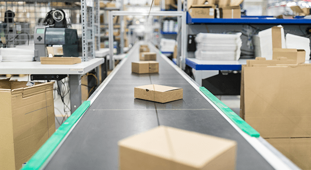 Cardboard boxes on a conveyor belt in a factory.